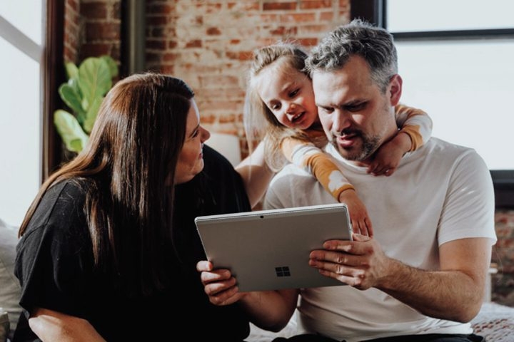 Two adults and a child looking at a tablet