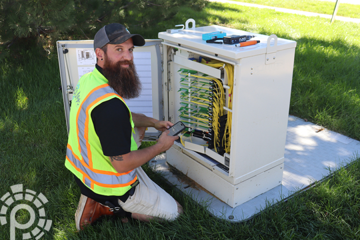 A Pulse field technician working at a fiber cable box.