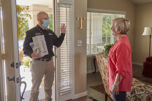 Image: A Pulse technician standing in the doorway of a home says hello the homeowner.