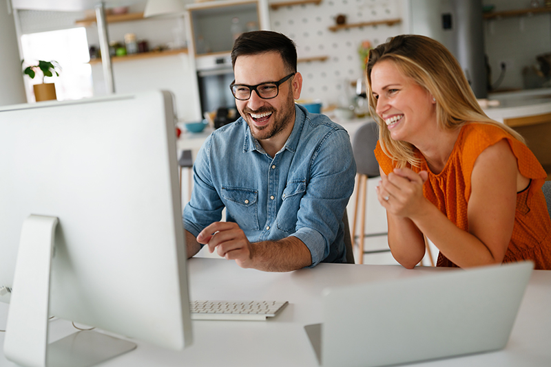 2 people looking at computer screens Image of two people looking at a computer screen and smiling