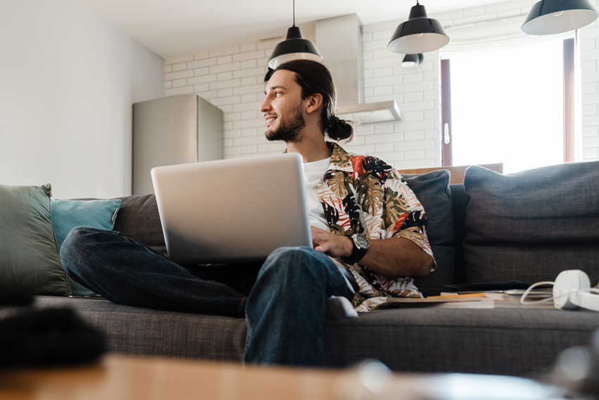 Man sitting on couch with laptop Image of man sitting on couch with laptop