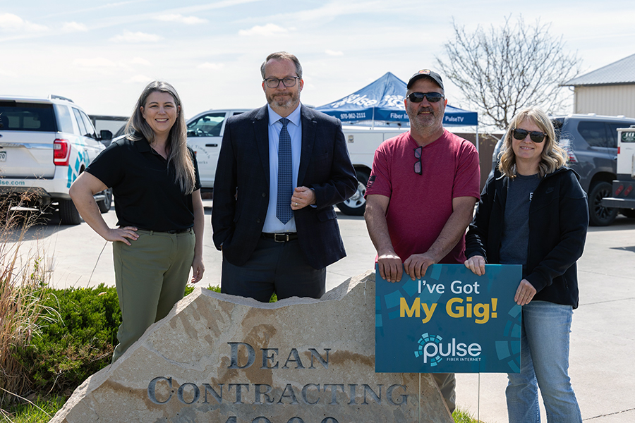 Photograph of 4 people surrounding a Dean Contracting monument sign. A man and woman are holding up a small Pulse sign that says I've Got My Gig.