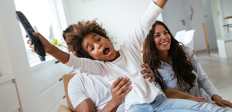 Family watches movie while sitting on the couch Plume Home