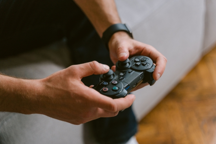 Pulse_FiberIsBetterForGaming_Blog Person holding a Playstation controller while sitting on a couch